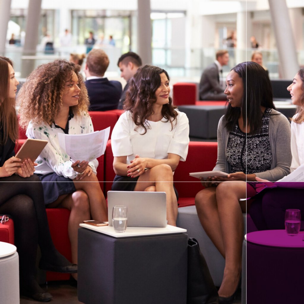 Group of women sat in the breakout space at a charity event. They are working, a laptop is on the table in front of them and they have note books.