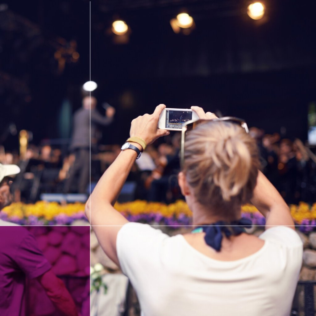 A woman taking a photograph using a mobile phone, the subject is the stage at an event.