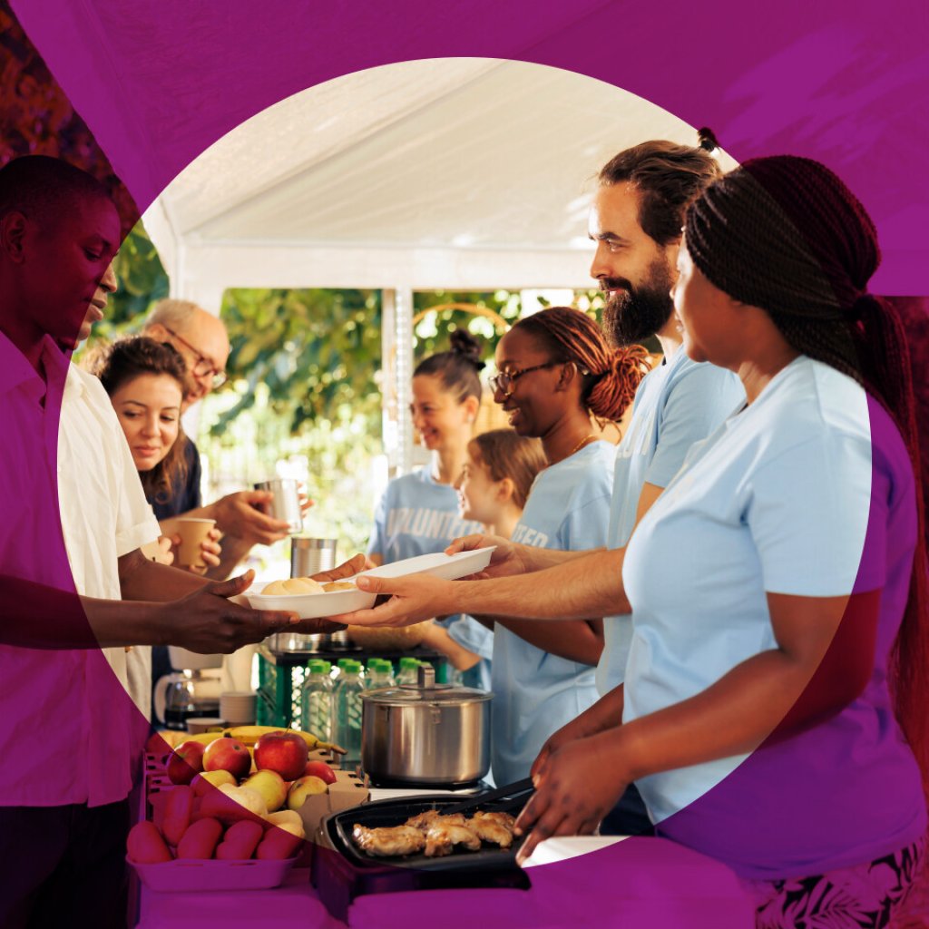 A group of charity workers, in matching clothes, serving food at an event.